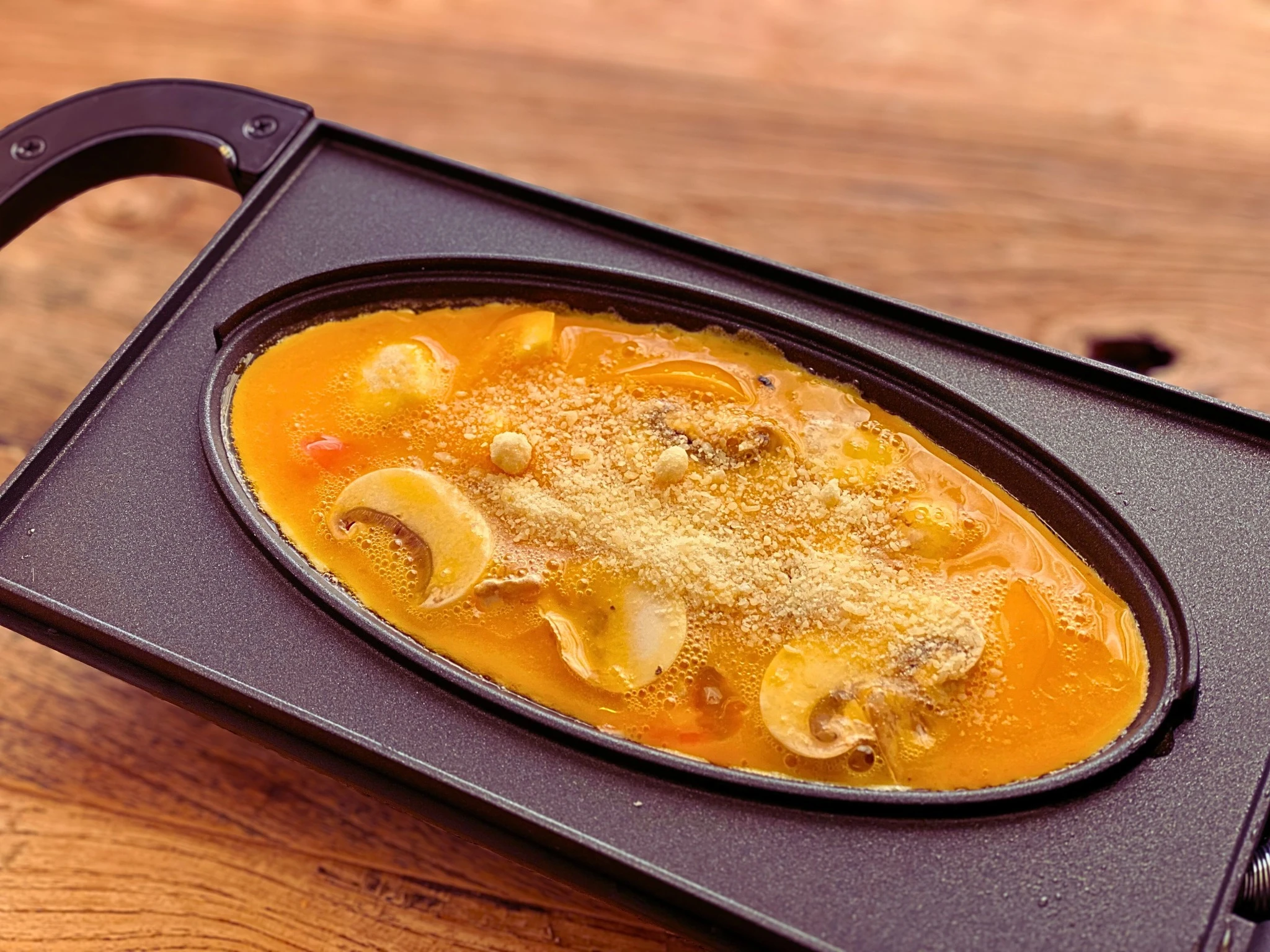 オムレツメーカーに卵液を流し入れる瞬間