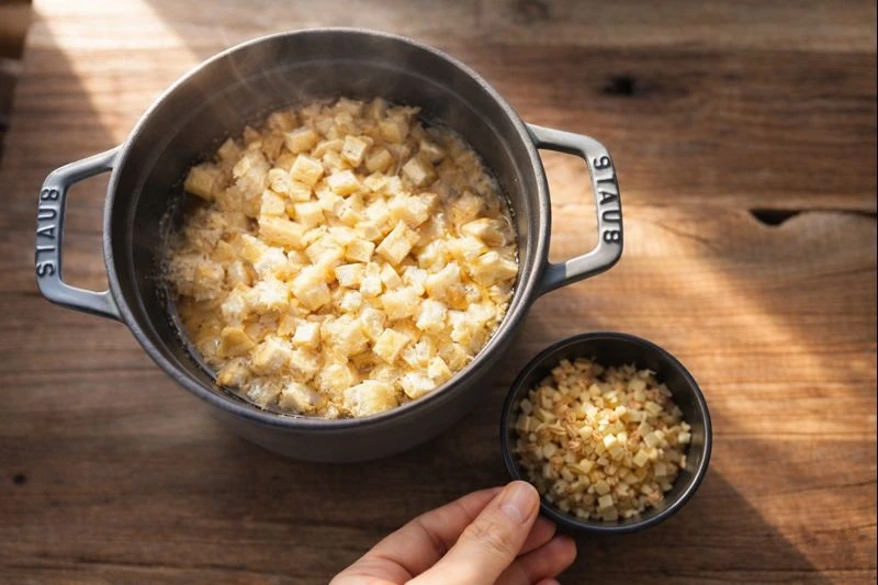 下茹でした大根と刻んだ油揚げが鍋に入った調理途中の様子。丁寧な下準備を感じる台所の風景