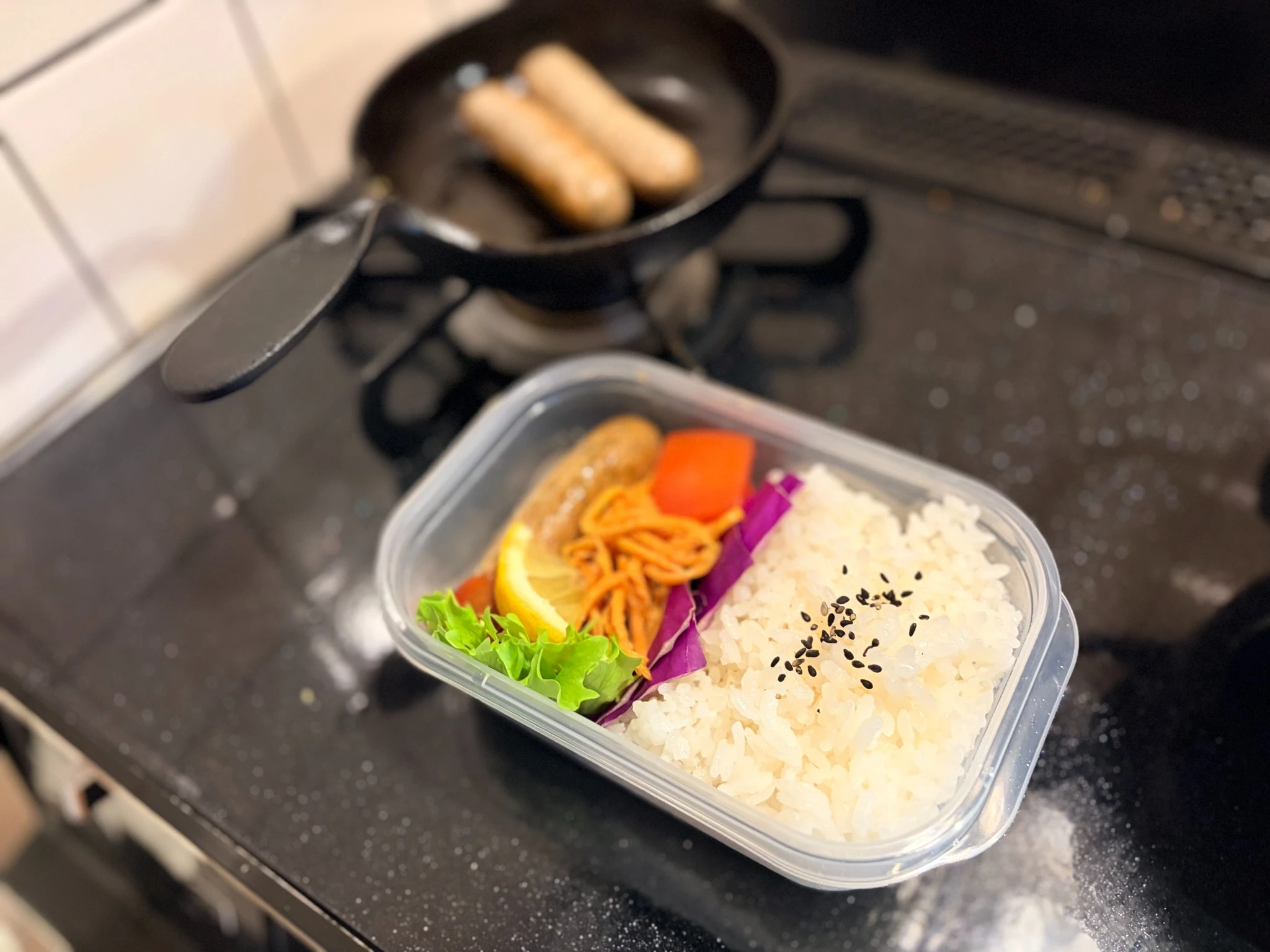 タッパーに詰めたごはんとにんじんのごまあえ、手作りソーセージのお弁当