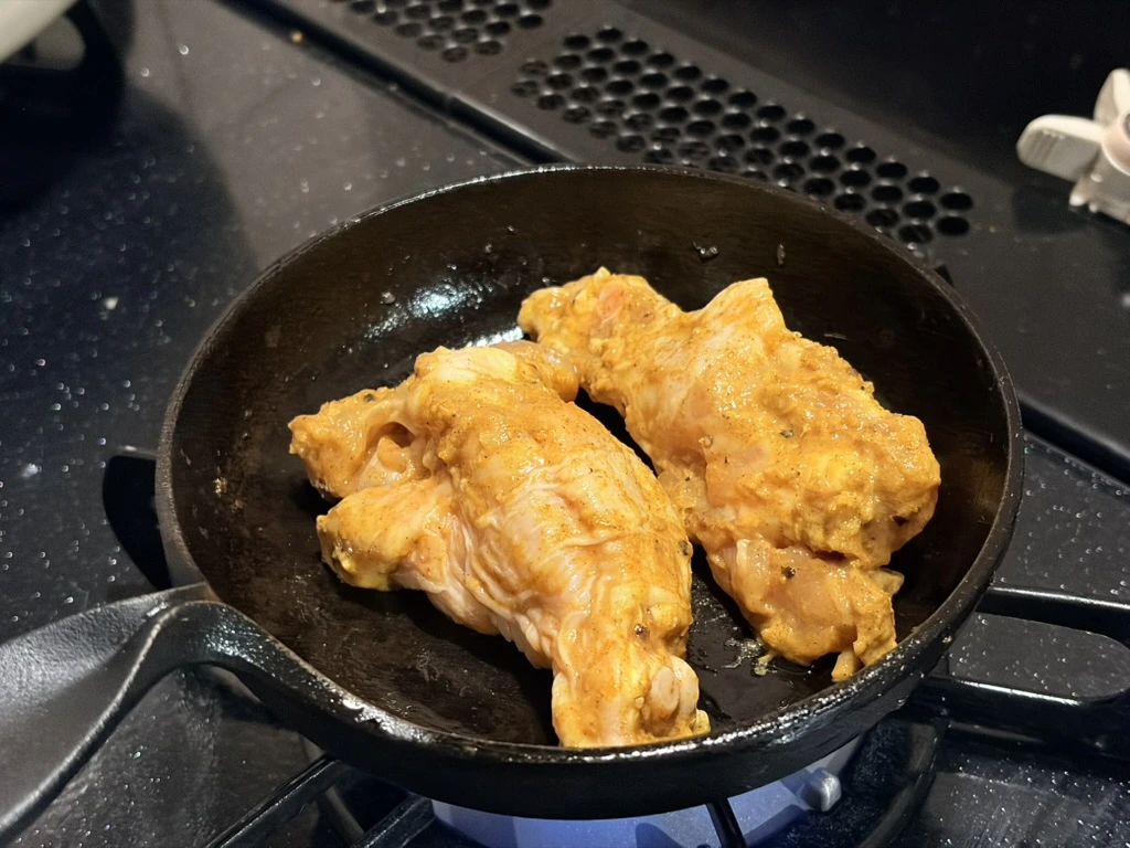フライパンで焼かれるタンドリーチキン風グリルチキン。香ばしいスパイスの焼き色