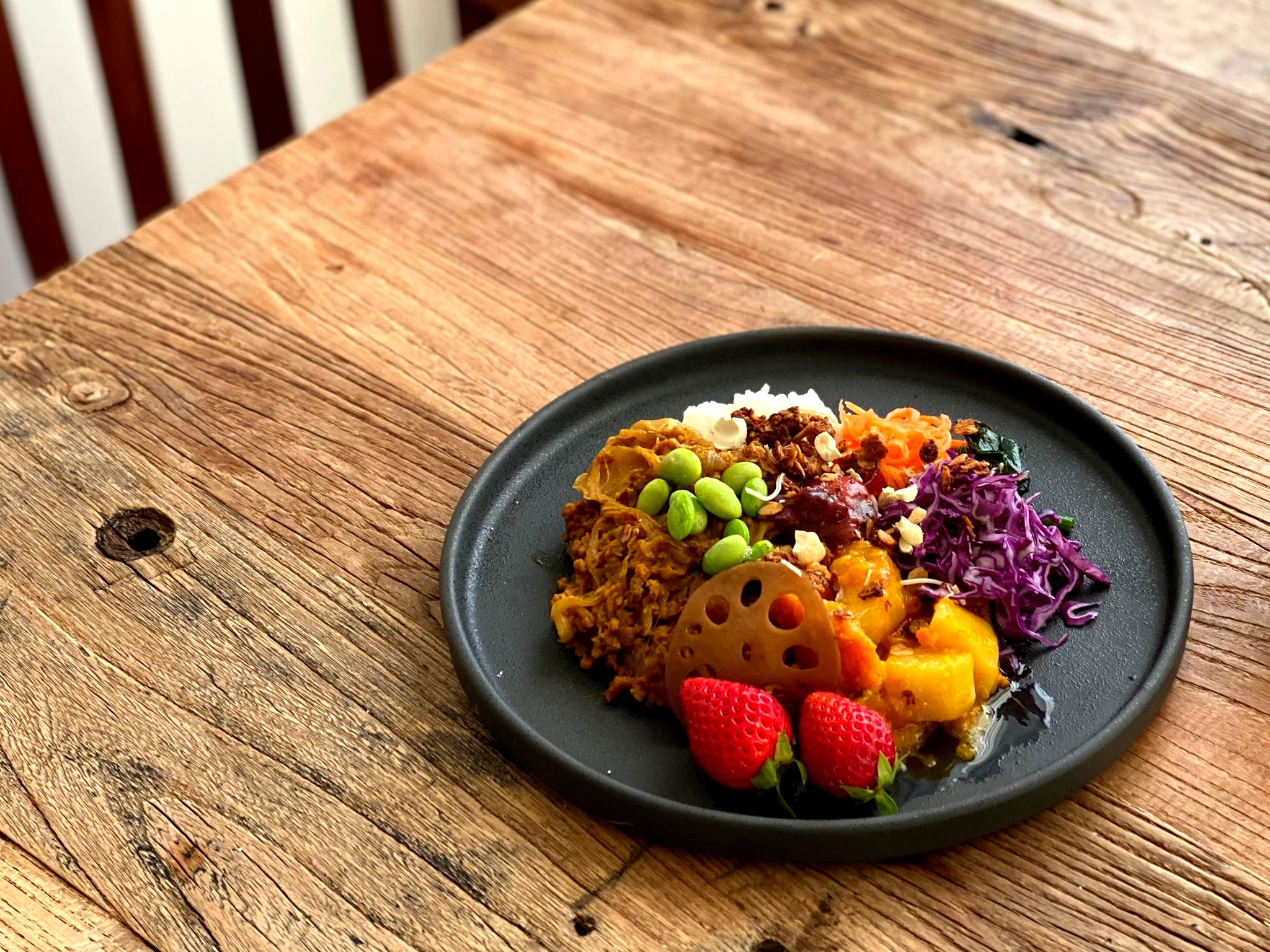 黒いプレートに大豆ミートや蓮根・苺・枝豆が彩り豊かに盛られたブッダボウル